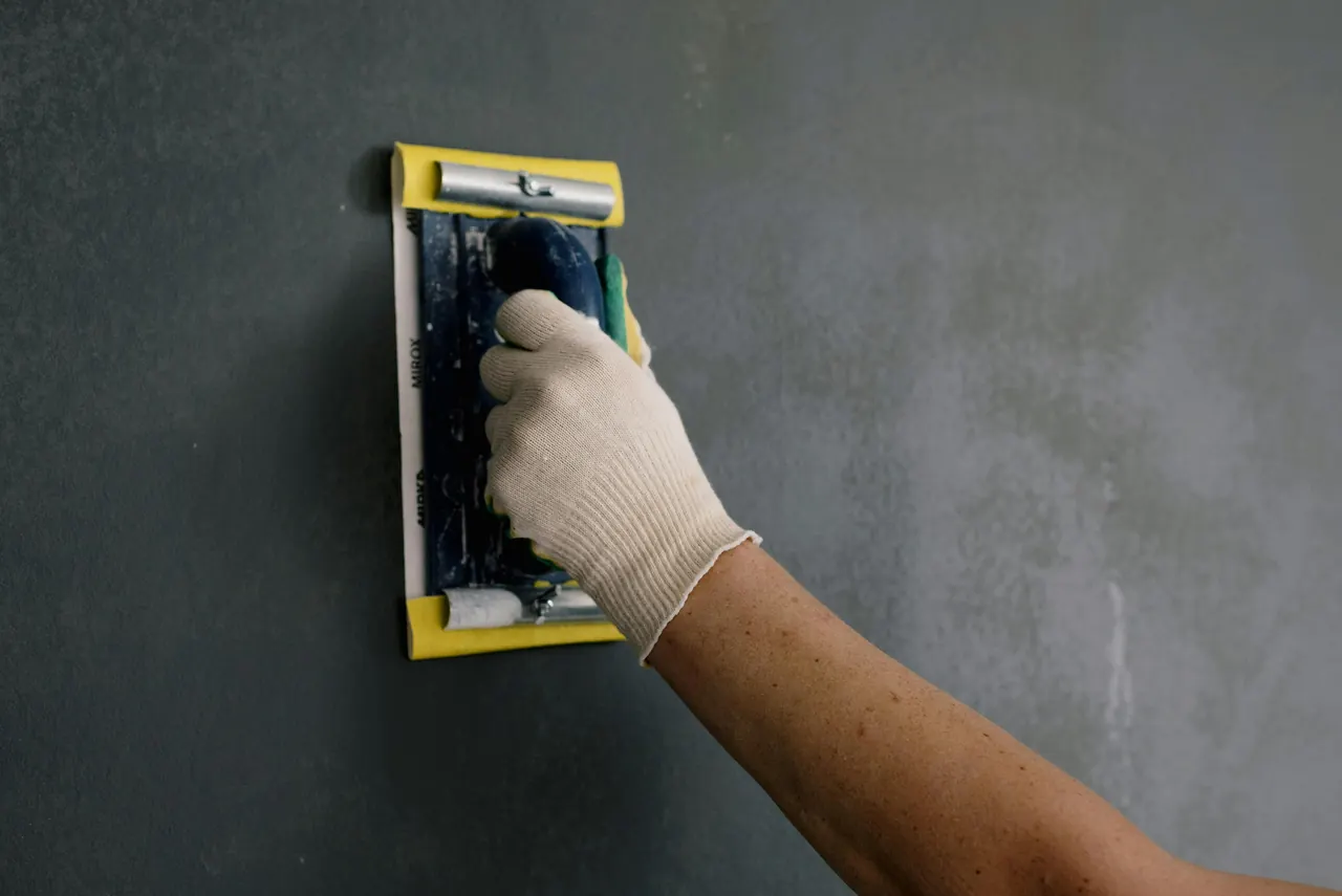 A worker sanding an interior wall during renovation